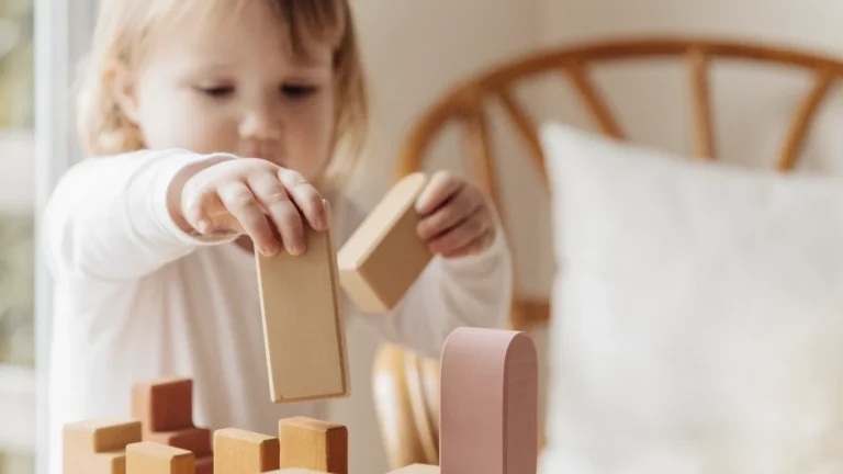 Criança pequena brincando com blocos de madeira sobre a mesa